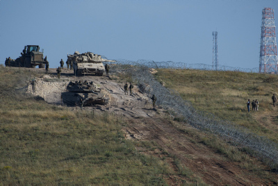 Israeli soldiers guard near an Israeli Merkava tank near the barbed wire fence in the Lebanon-Israel 'Blue Line', near Misgav, northern Israel