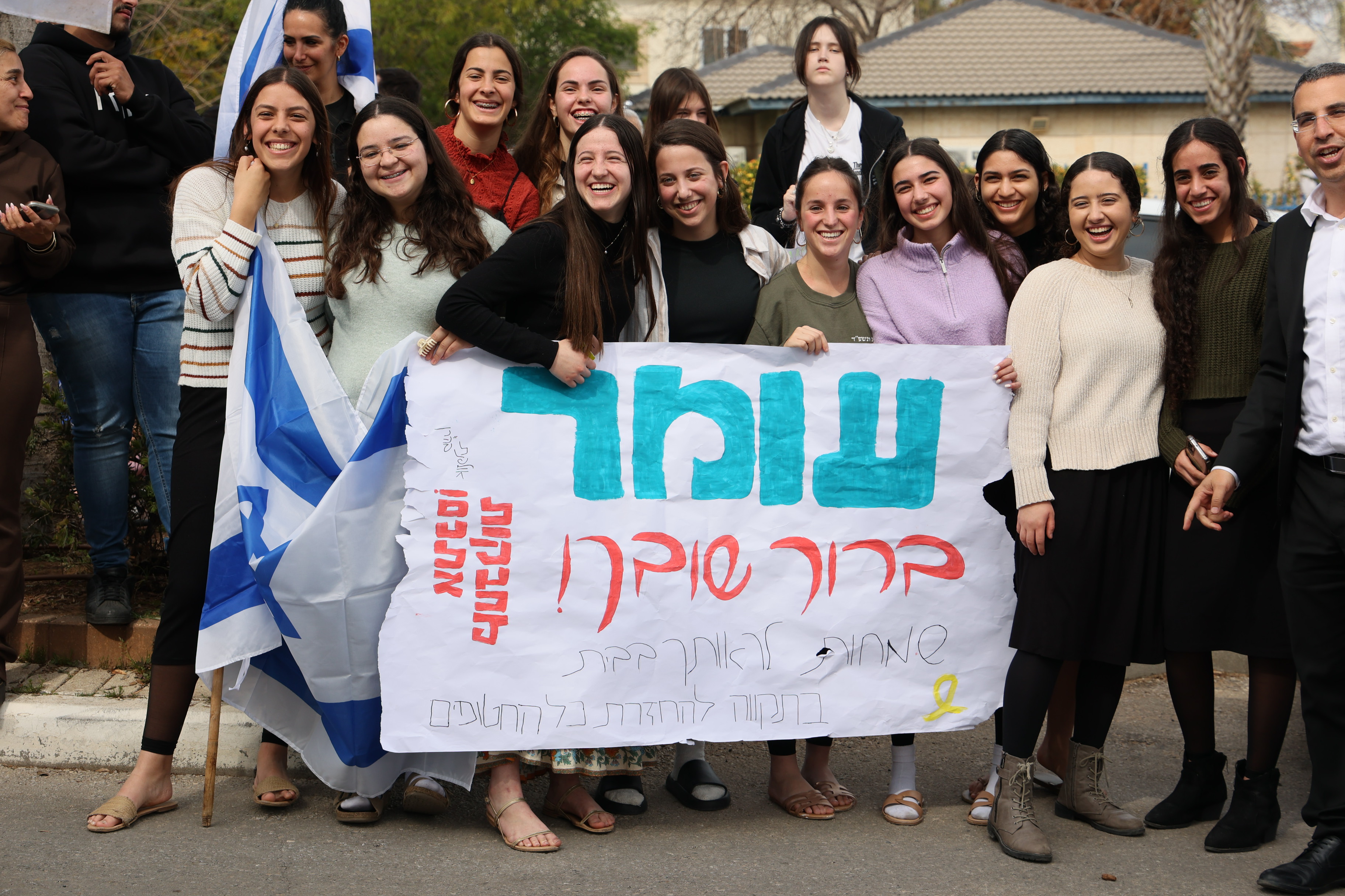 People wait for the arrival of former hostage Omer Wenkert outside his home in Gedera, on March 4, 2025. 