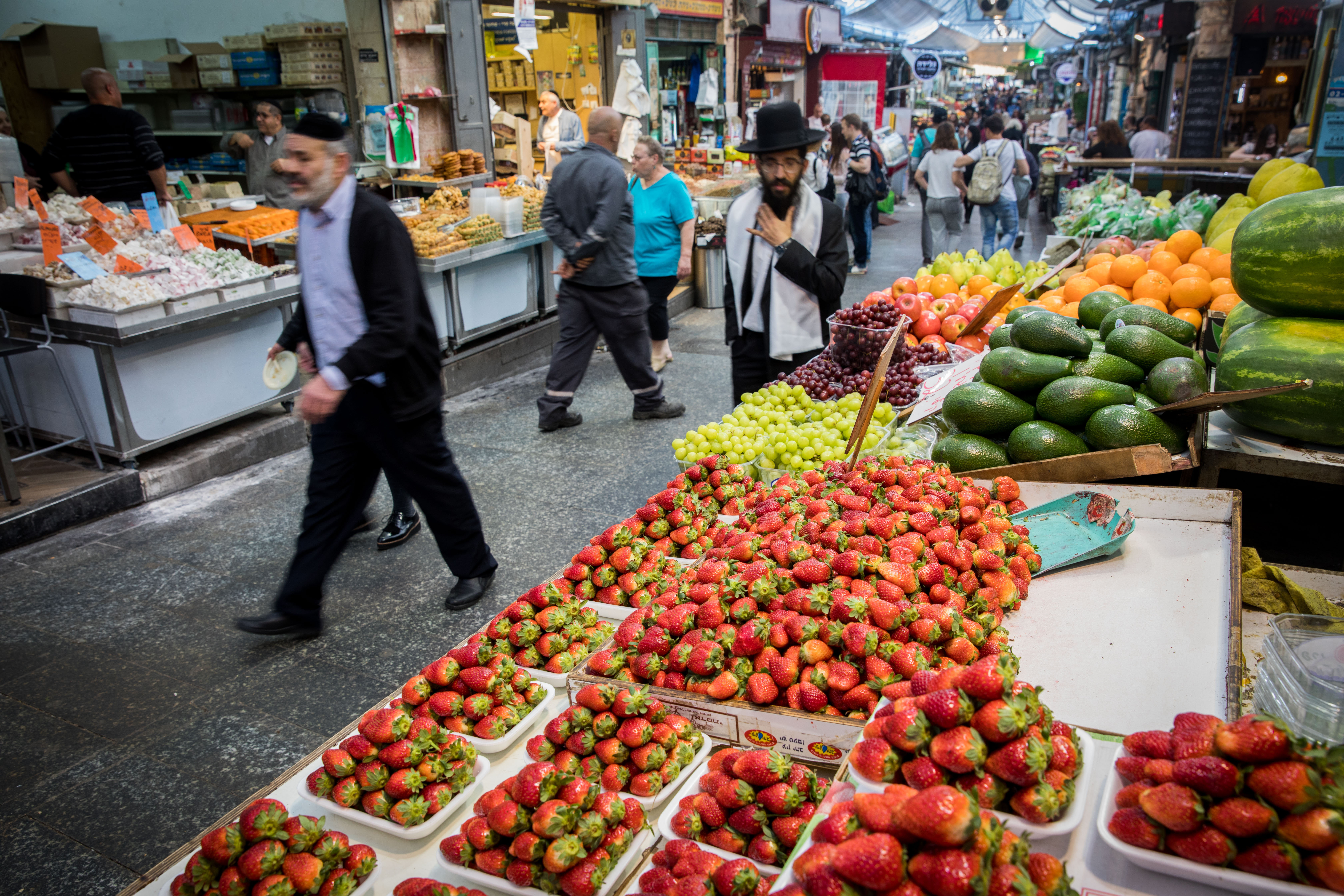 People walk near a stand at the Mahane Yehuda market in Jerusalem