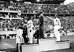 Owens salutes the American flag after winning the long jump at the 1936 Summer Olympics.