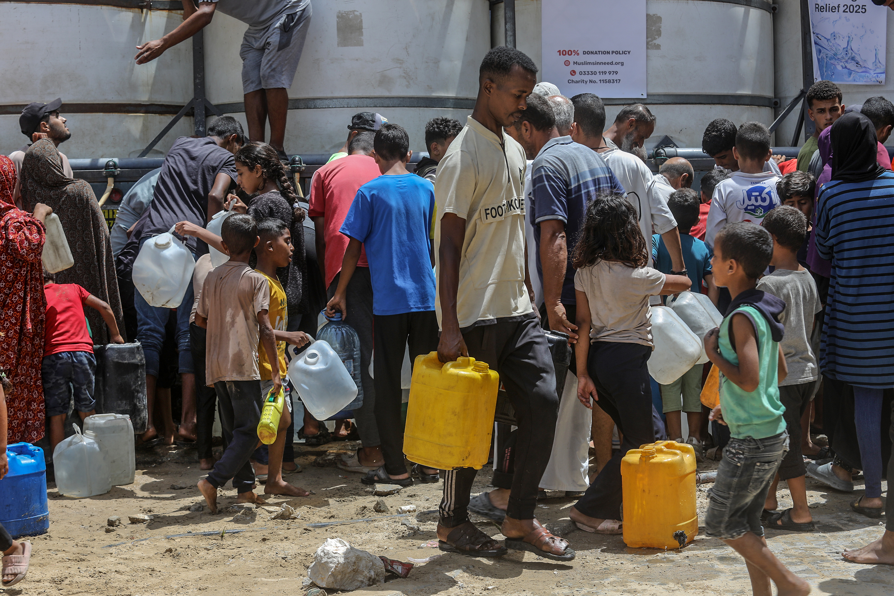 Palestinians collect drinking water in Khan Yunis, in the southern Gaza Strip, August 19, 2025. 