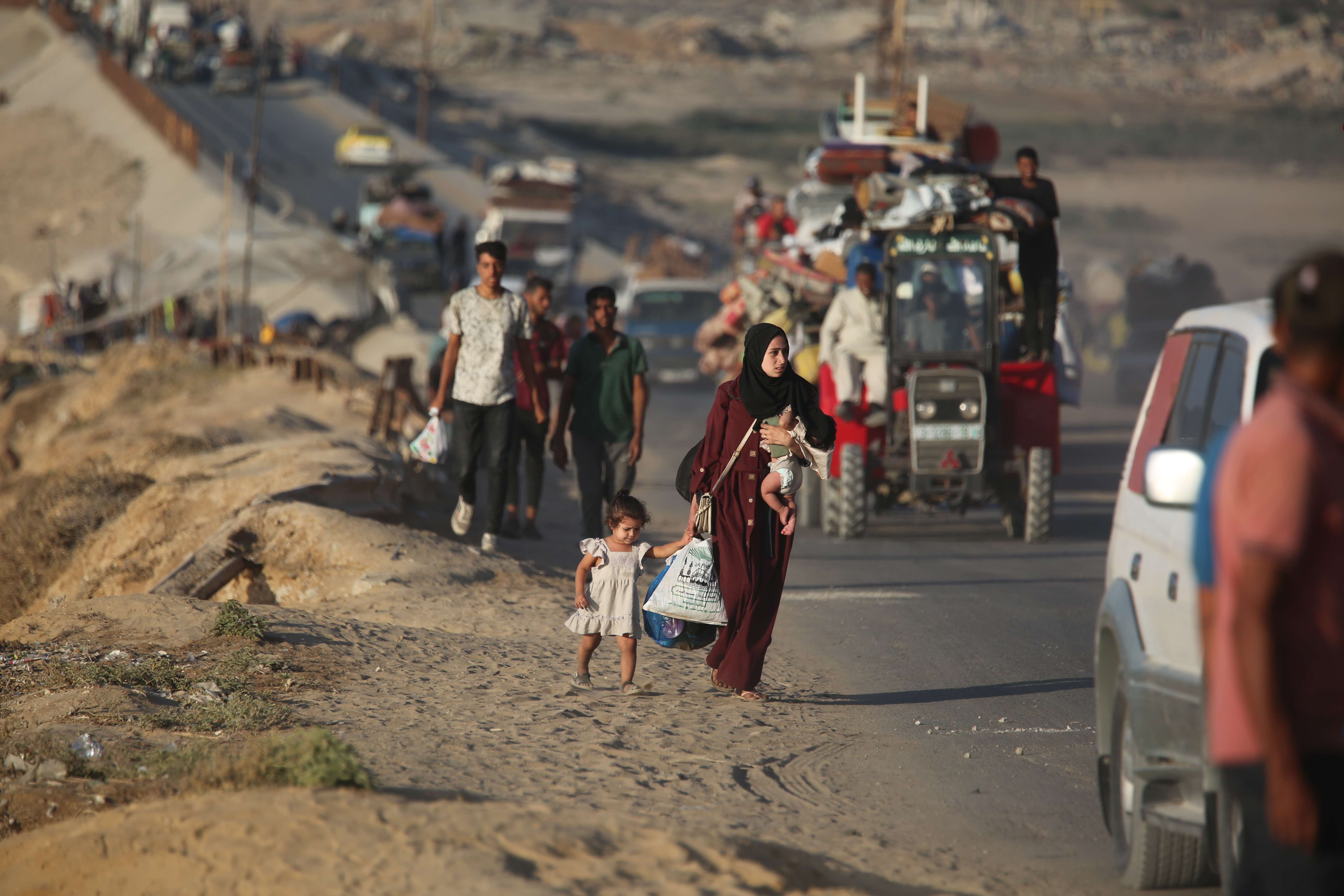 A truck towing a cart and transporting evacuees fleeing southbound from Gaza City moves along the coastal road.
