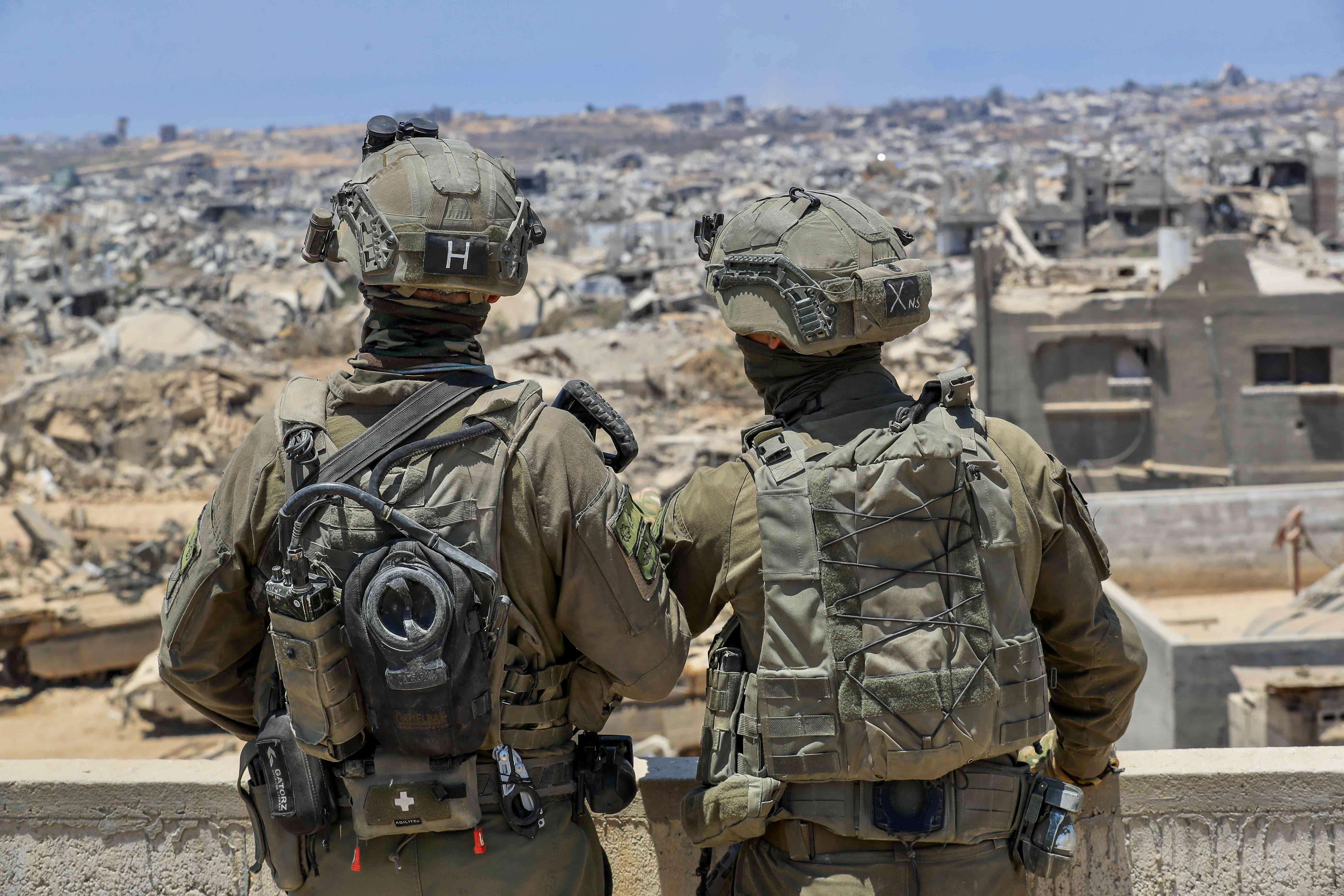 IDF soldiers look at Gaza