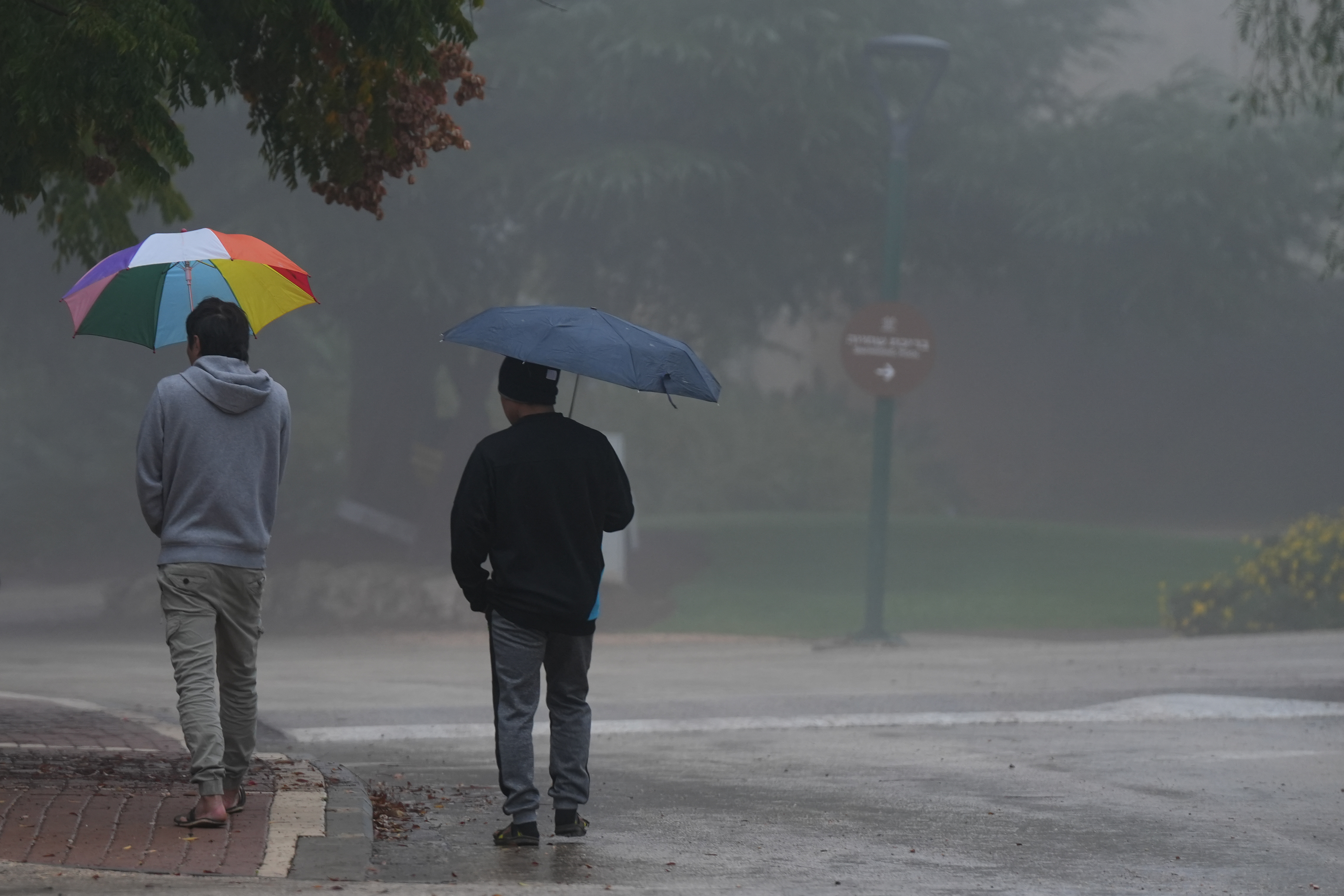 People walk on a foggy, rainy day in Kibbutz Malkia, near the border with Lebanon, on December 10, 2025.