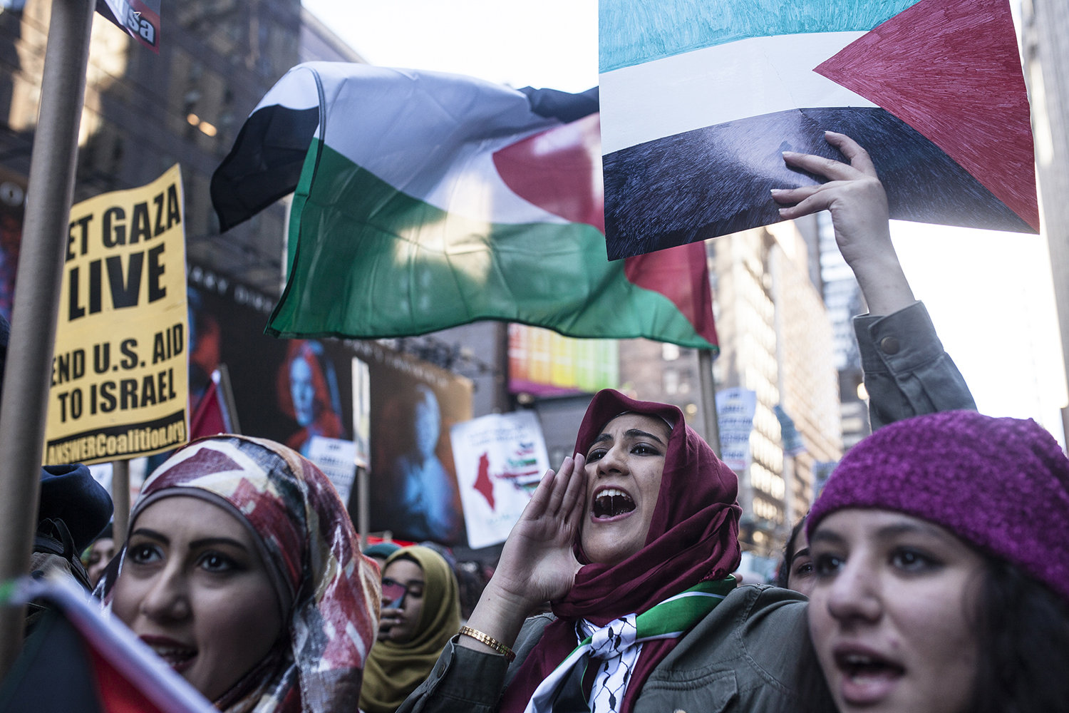 pro-Palestine demonstrators chants chant slogans and hold up signs as they march next to a Pro-Israel protest in Times Square, New york on October 18, 2015.