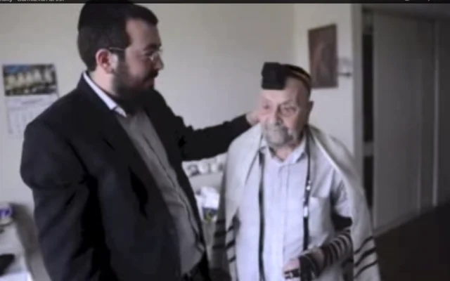 Rabbi Schlanger assisting an elderly Soviet Jew to put on tfilin for the first time.