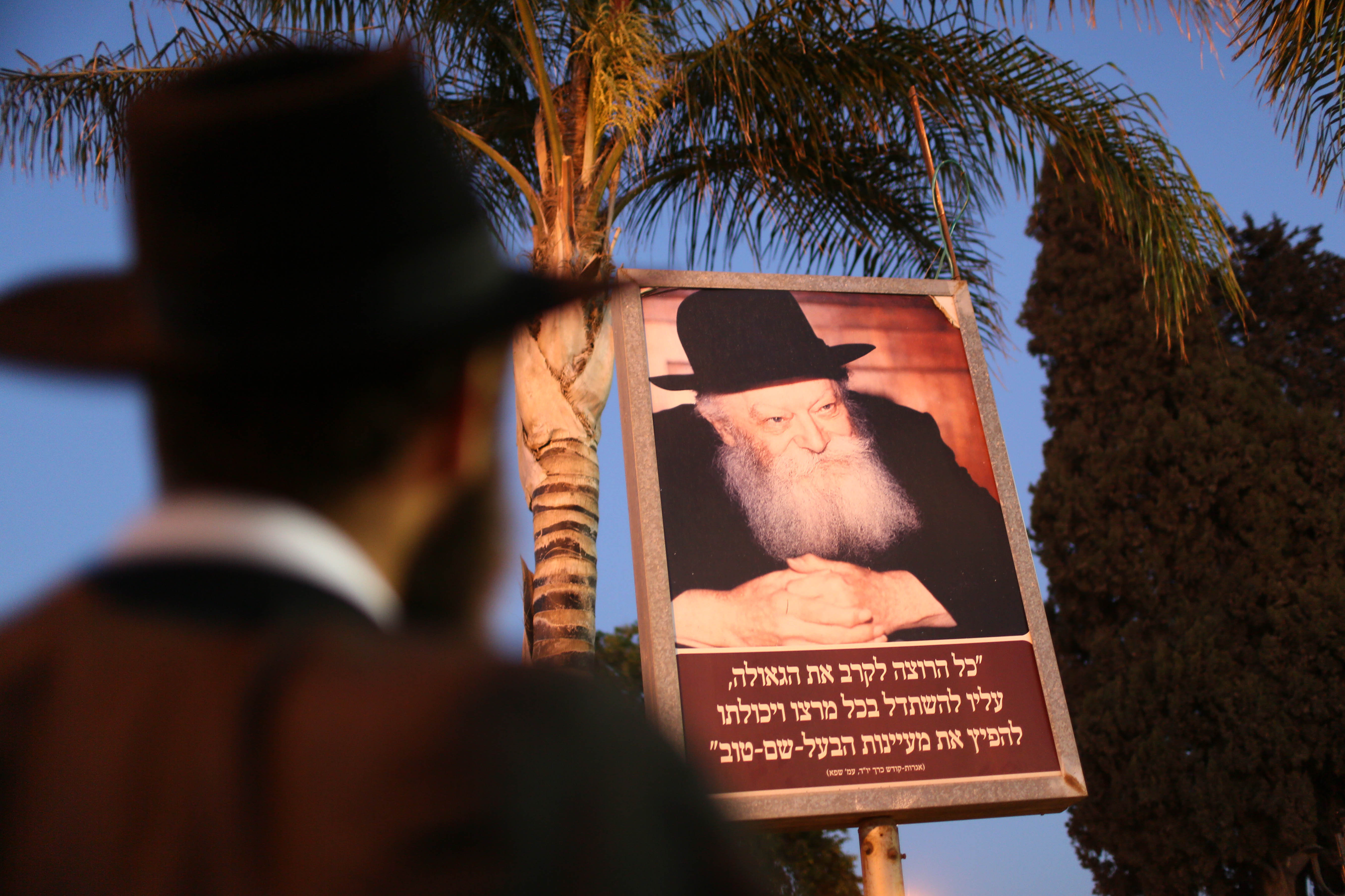 An ultra orthodox Jewish man looks up at a sign featuring the Lubavitcher Rebbe. Kfar habad, Aug 26 2012.