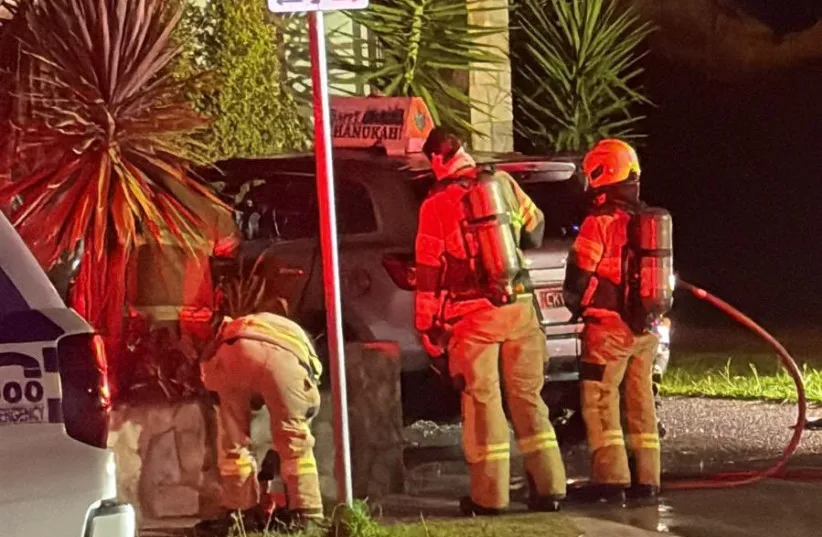 Emergency services responding to the rabbi's firebombed car, with the Happy Chanukah sign visible.