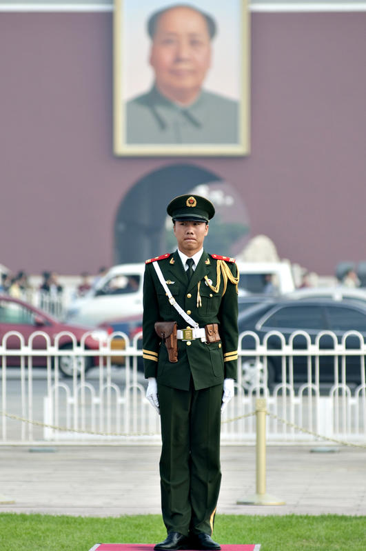 A chinese security guard stands below a portrait of former Chinese leader Mao Zedong in the Tiananmen Square in Beijing, the world's largest public square. September 14, 2009.