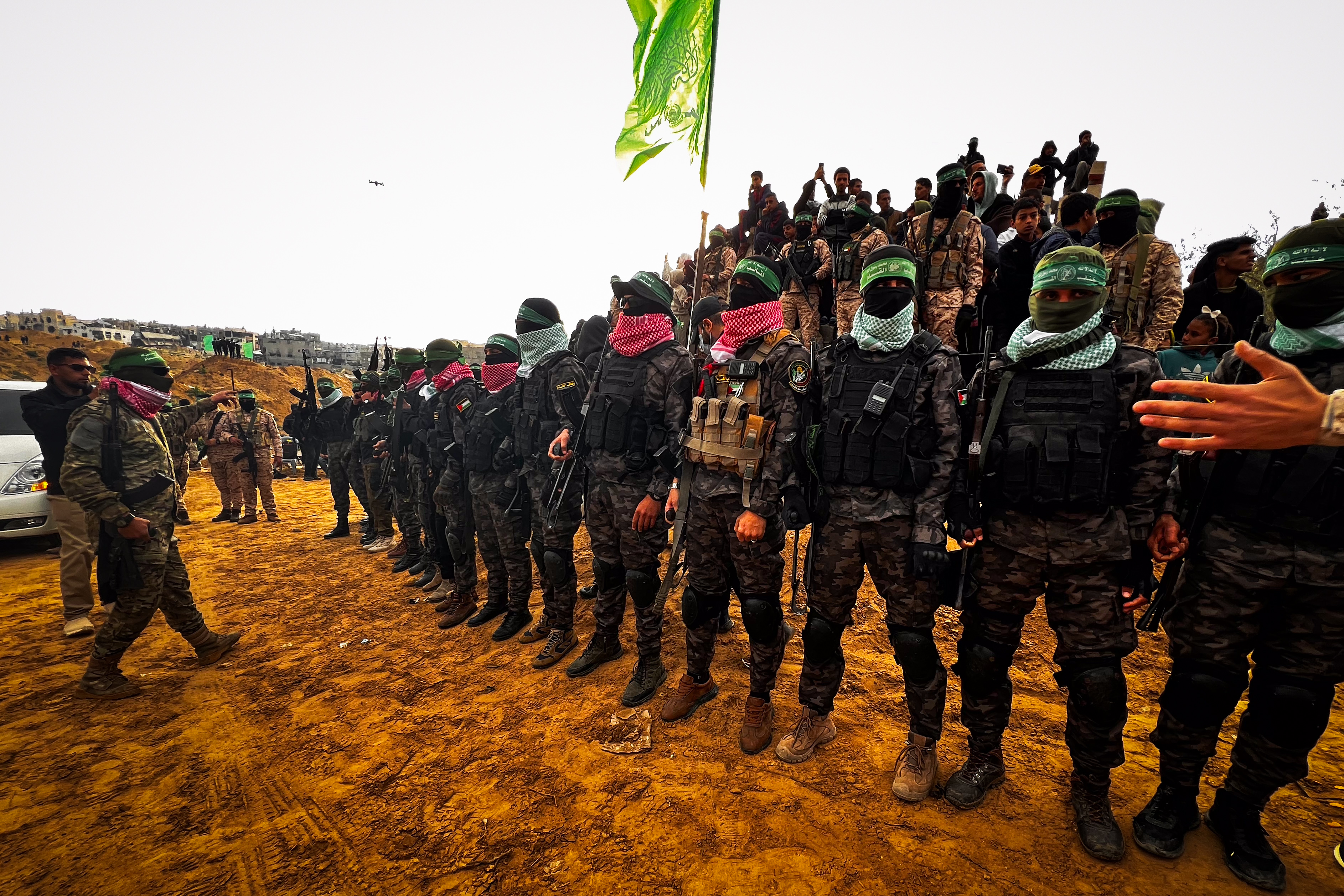 Members of the Al-Qassam Brigades guard while Palestinians waiting for the hand over of the bodies of four late Israeli hostages to the Red Cross, as part of the ceasefire agreement between Israel and Hamas, in Khan Yunis, February 20, 2025.