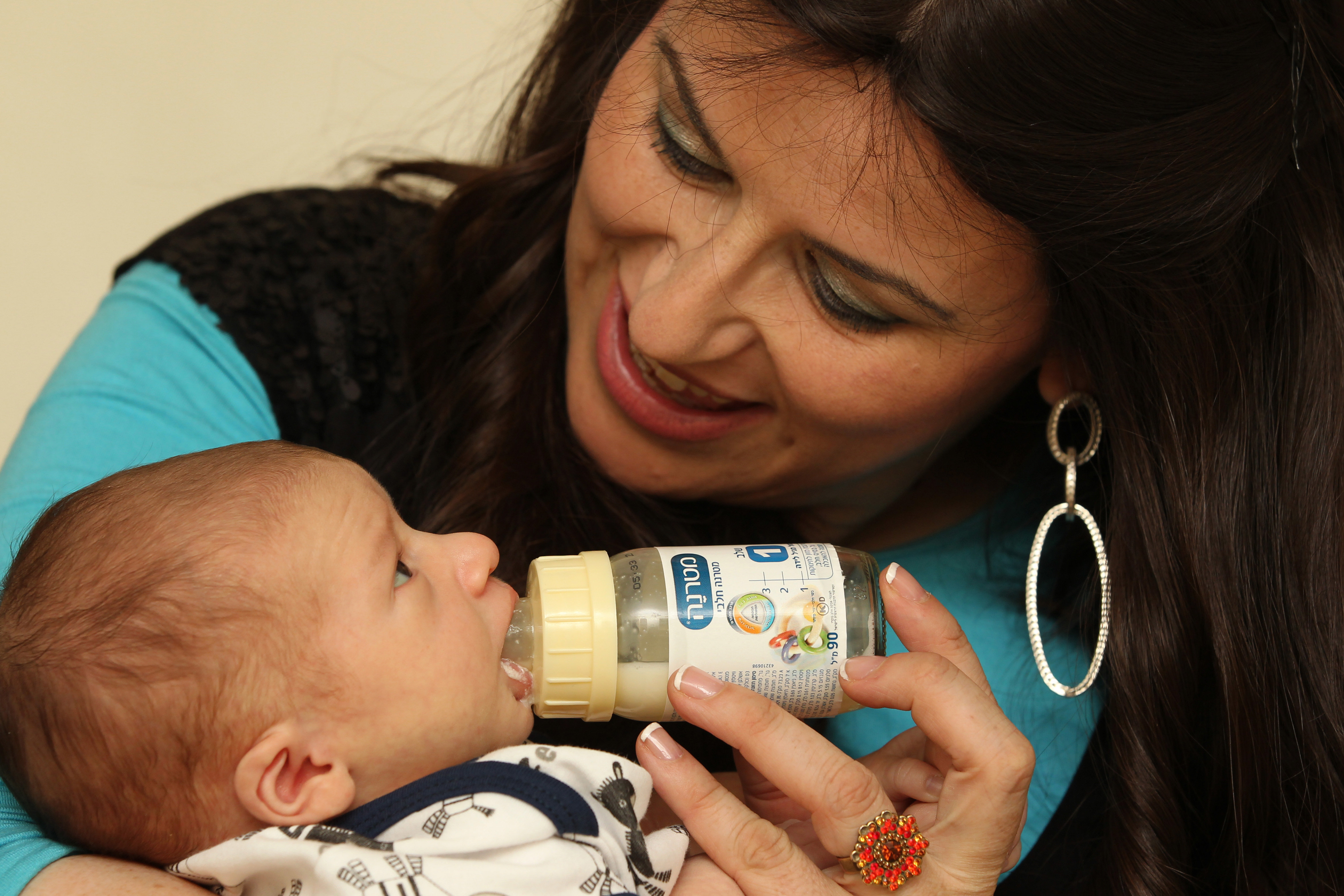 A mother feeds her two week old baby with milk substitute. February 28, 2011. Illustration.