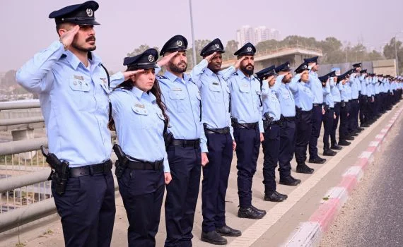 Israeli police officers saluting ran Gvili on his final journey