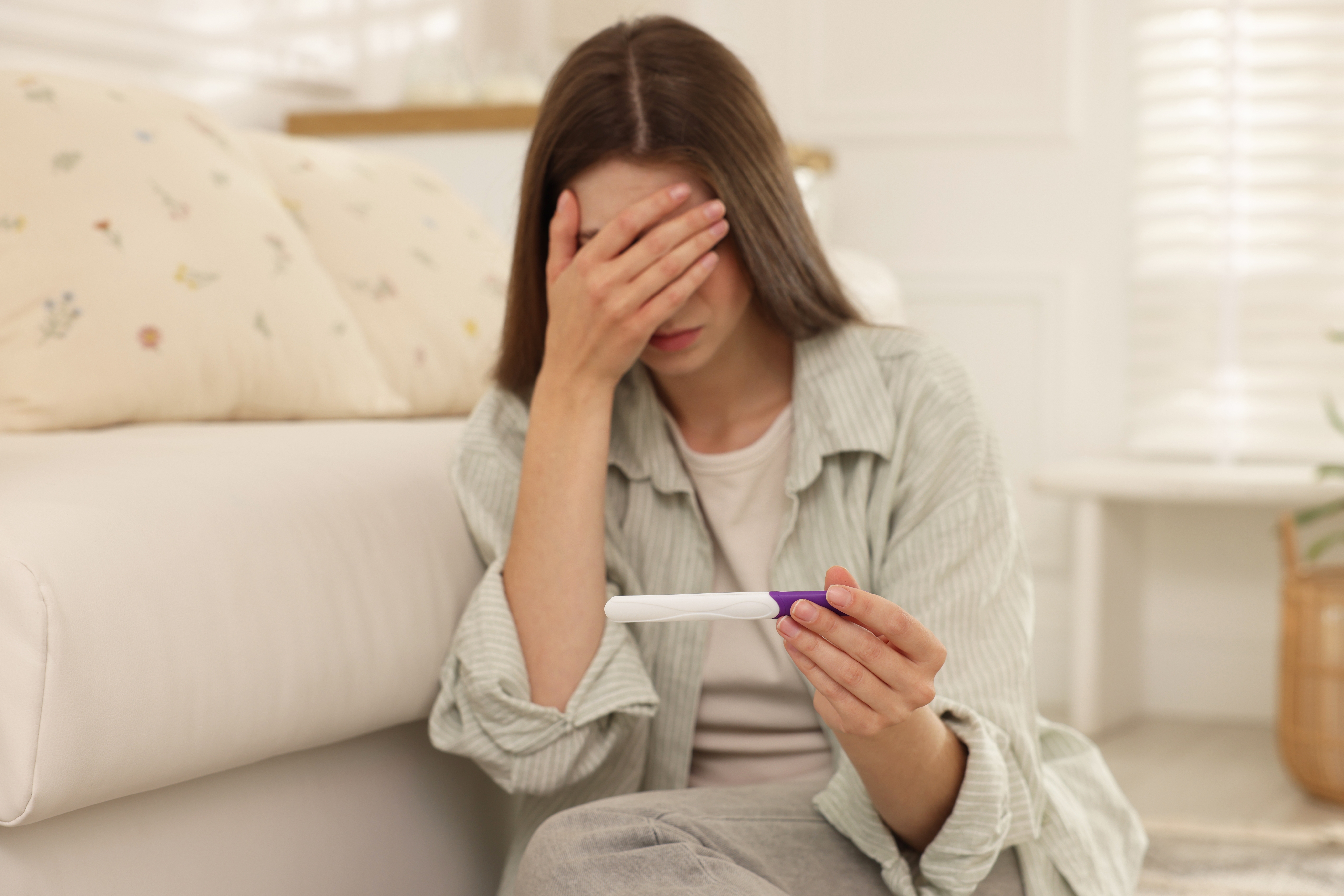 Sad woman looking at pregnancy test (Illustration ONLY)