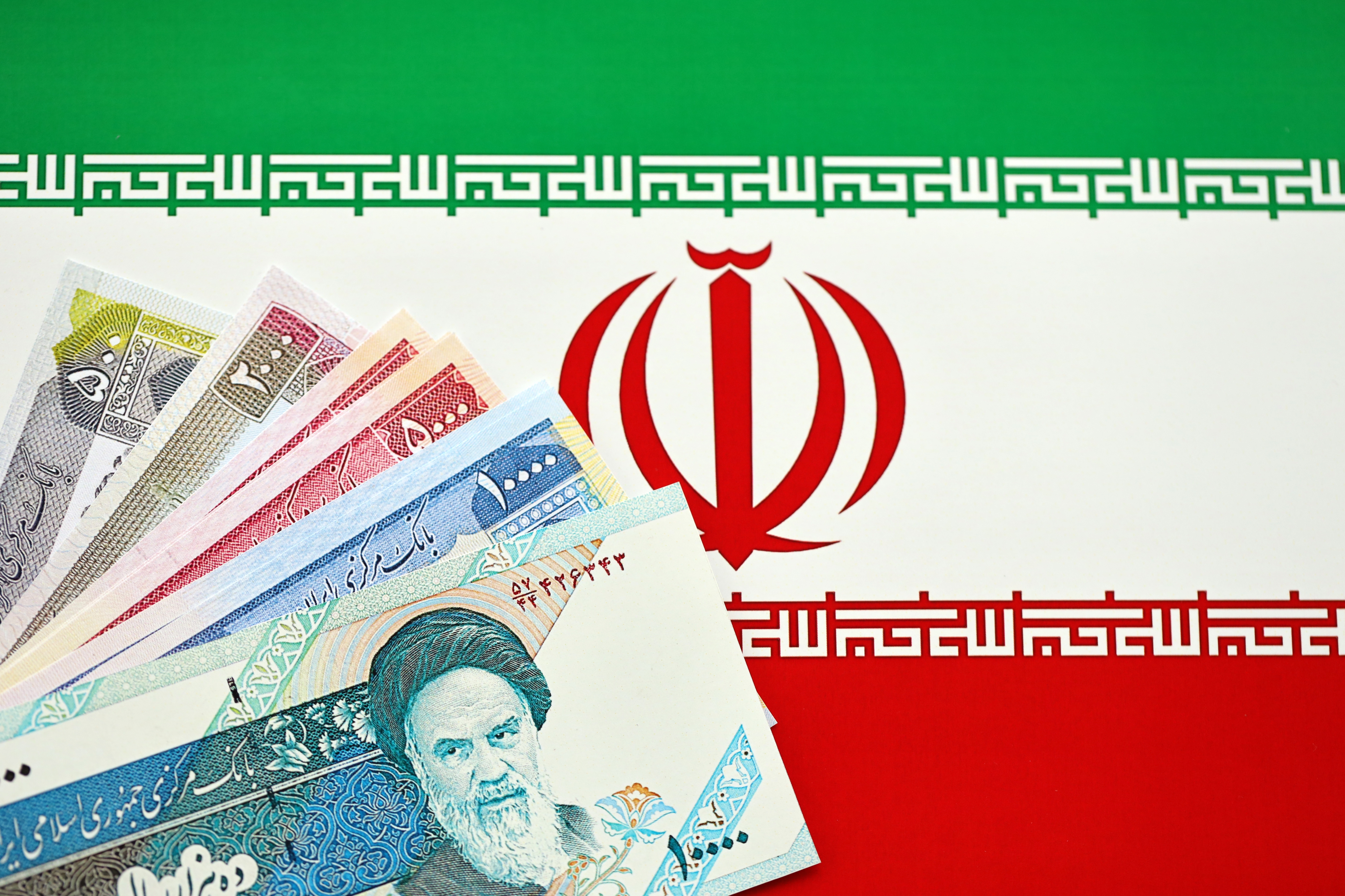 Iranian Rial IRR banknotes from Iran on flag of Islamic Republic of Iran close up