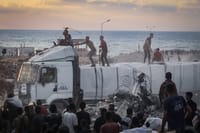 Armed Palestinians sit on trucks carrying humanitarian aid near the Zikim border crossing between Israel and Beit Lahia in the northern Gaza Strip, August 18, 2025.
