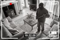 CCTV surveillance security camera of burglar breaking into home via back door window with crowbar (house robbery concept)