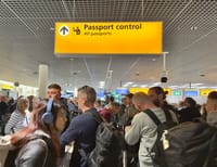 Passengers waiting in line to clear passport control at Amsterdam Schiphol Airport.