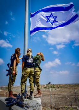 Israeli soldier hang an Israeli flag in Kibbutz Nir Am, near the Israeli border with the Gaza Strip, August 12, 2024.