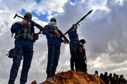 Members of the Al-Qassam Brigades guard while Palestinians waiting for the hand over of the bodies of four late Israeli hostages to the Red Cross, as part of the ceasefire agreement between Israel and Hamas, in Khan Yunis, February 20, 2025.