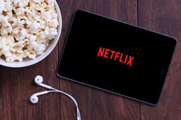  Table with popcorn and Netflix logo on Apple Ipad mini and earphones