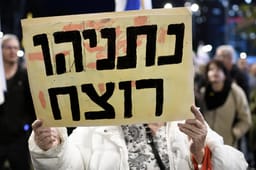 An Israeli woman holds a placard reading "Netanyahu is a murderer" as thousands of Israelis protested against the government, March 22, 2025 in Tel Aviv, Israel. 