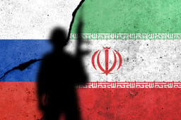 Flags of Russia and Iran painted on the concrete wall with soldier shadow. See less 