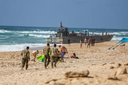 US navy soldier and Israelis near a US Army vessel that washed up on the beach in the southern Israeli city in Ashdod, May 25, 2024