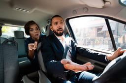 Taxi driver driving a car and having an argument with female passenger. 