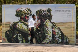 An ultra orthodox Jewish man walks past a public bombshelter with illustration of Israeli soldiers, in Northern Israel. September 10, 2025.