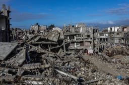 Palestinians seen near buildings destroyed in the recent war, in Khan Yunis, in the southern Gaza Strip, December 30, 2025.