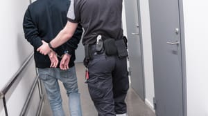 Prison guard escort arrested inmate through jail corridor