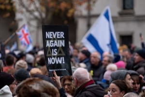Crowds holding banner saying 'Never Again is Now', at the March Against Antisemitism