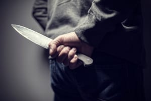 Criminal with knife weapon hidden behind his back