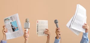 Female hands with microphones and newspapers on beige background 