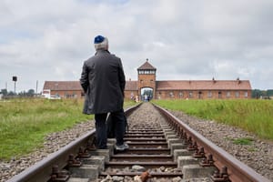 Jewish man stands in front of Auschwitz