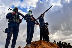 Members of the Al-Qassam Brigades guard while Palestinians waiting for the hand over of the bodies of four late Israeli hostages to the Red Cross, as part of the ceasefire agreement between Israel and Hamas, in Khan Yunis, February 20, 2025.