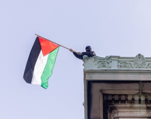 NEW YORK, N.Y. – April 30, 2024: A demonstrator waves a Palestinian flag on the roof of Hamilton Hall at Columbia University in Manhattan.
