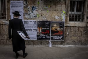 Ultra Orthodox Jews walking next to a Pashkevil on the IDF draft law in the ultra orthodox neighborhood of Mea Shearim, in Jerusalem, March 15, 2024. 