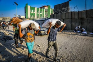 Palestinians walk through the streets with bags of flour after humanitarian aid trucks arrived via the Kerem Shalom crossing into southern Gaza, in Khan Yunis, July 24, 2025.