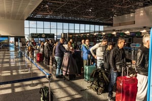 Passengers with luggage queue at milano malpensa airport check-in area