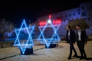 People walk next to a Menorah (Hanukkah lamp) in a shape of a david star ahead of the Jewish holiday of Hanukkah, outside Jerusalem's Old City, December 13, 2025. 