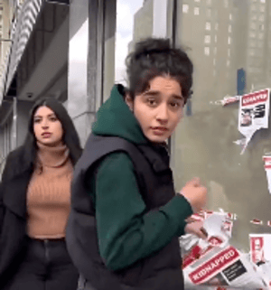 Aya and Dana Baraket tearing down posters of kidnapped Israeli children 
