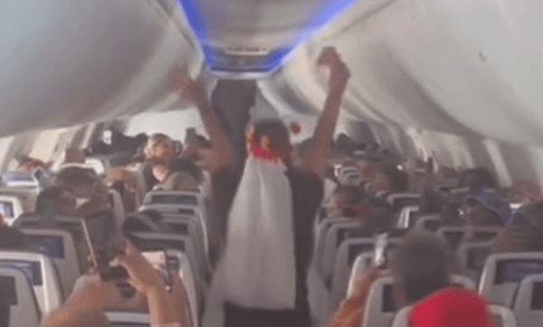 The bride cheers during the "wedding ceremony" on the plane.