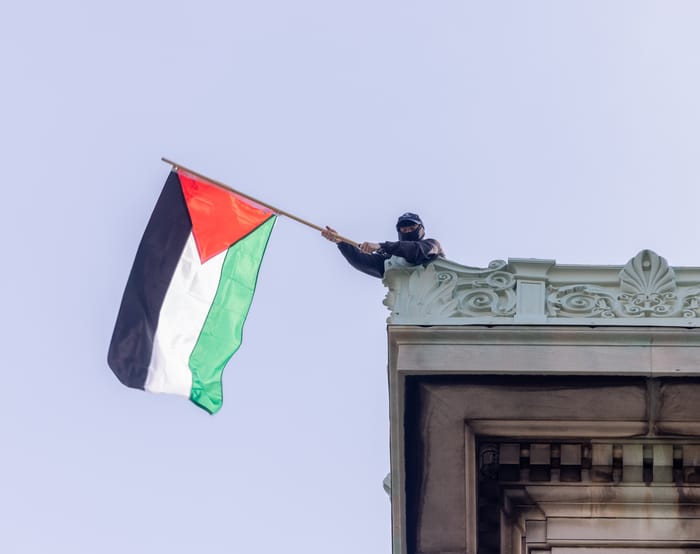 NEW YORK, N.Y. – April 30, 2024: A demonstrator waves a Palestinian flag on the roof of Hamilton Hall at Columbia University in Manhattan.