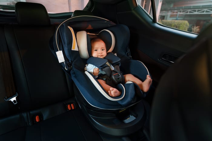happy newborn baby sitting in an infant car seat