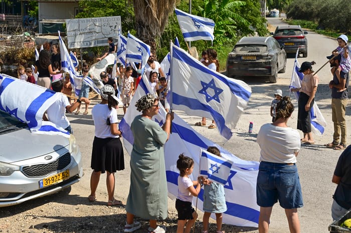 Hundreds of family, friends, and residents of the Golan Heights stand vigil with the national flag to accompany the parents of late IDF soldier Bezalel Yehoshua Mosbachere