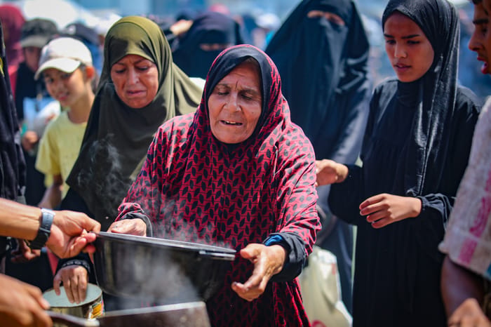 Palestinians receive meals from volunteers in Gaza City, on July 25, 2025.