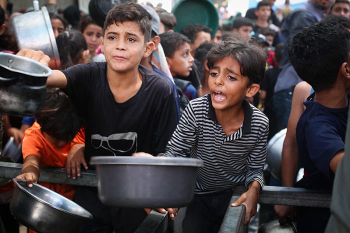 Palestinians receive meals from volunteers in Gaza City, on August 18, 2025.