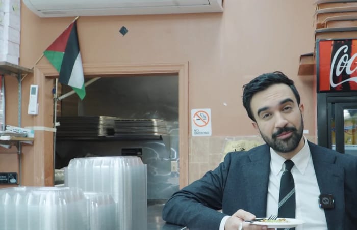 Mayor-Elect Mamdani with a Palestinian flag in the background.
