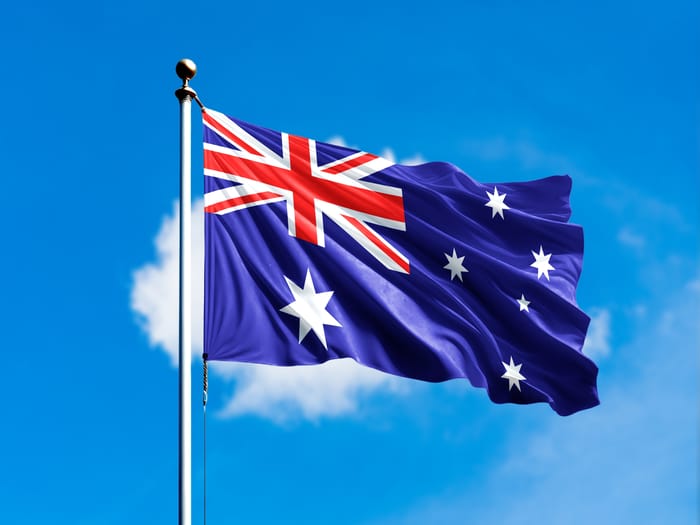 Australia flag flying on blur blue clouds background.
